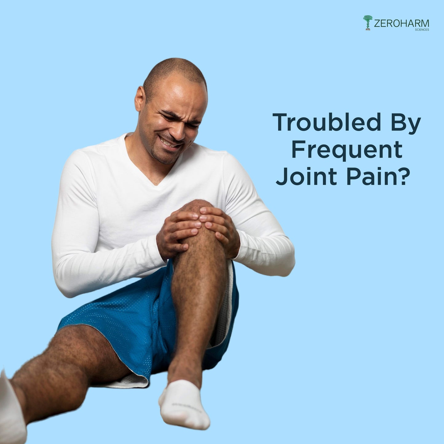 Man in sportswear sitting against a blue background, holding his knee with a pained expression to represent frequent joint pain or joint discomfort.