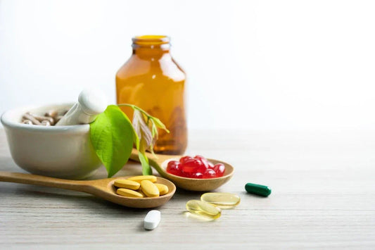 An image of various dietary and nutritional supplements, including capsules and gummies, alongside an amber bottle and a bowl of herbs, representing health and wellness.