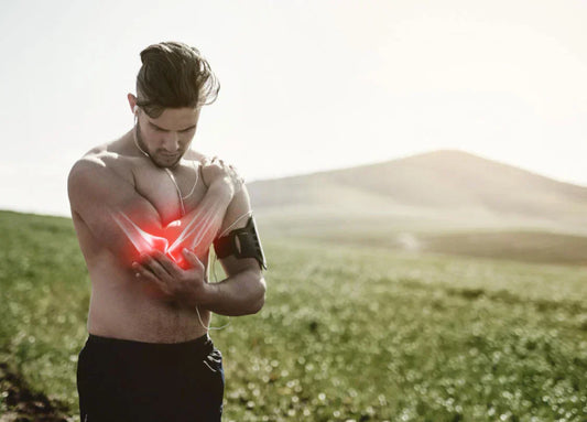 A man holding his arm in pain in an outdoor setting, with a red glow indicating discomfort, symbolizing the impact of Vitamin D deficiency on bone strength and the immune system.