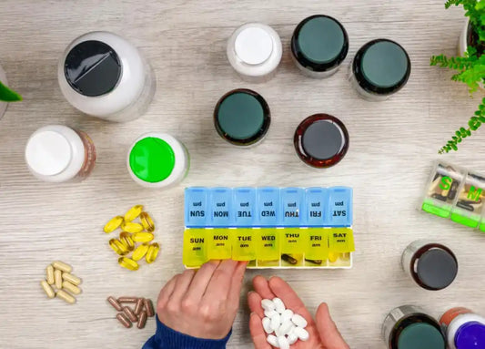 An image showing a person organizing a variety of dietary supplements in a pill organizer, with bottles of supplements and capsules arranged around it, symbolizing a wellness supplement stack.